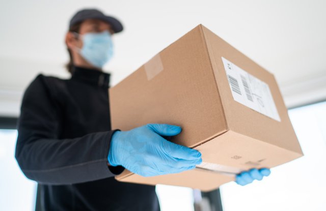 Home delivery shopping box man wearing gloves and protective mask delivering packages at door.